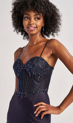 Woman wearing the Colette CL8515 long prom dress, featuring dark beaded lace, thin straps, and a sweetheart neckline, smiles and poses against a plain light background.