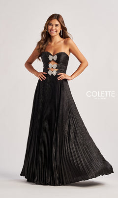 A woman stands against a plain background in the Colette CL8520 strapless pleated long prom dress featuring silver butterfly accents and rhinestone bows on the bodice, with the "Colette by Daphne" logo visible.