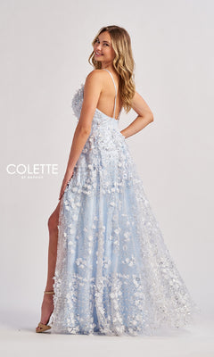 A woman in the Colette CL8525 long prom dress—a light blue, floor-length A-line gown with spaghetti straps and flower embellishments—stands sideways, smiling against a plain background.