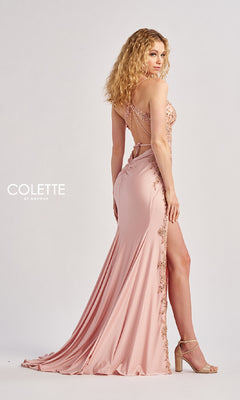 A woman models the Colette CL8535 long prom dress—a blush pink, floor-length gown with lace embroidery, v-neckline, thin straps, high slit, open back, and an elegant look—posing sideways against a plain background.