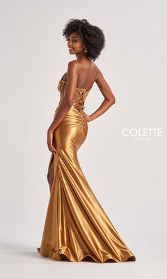 A woman models the Sheer-Bodice Long Prom Dress Colette CL8560, a strapless gold satin gown with a corset bodice, lace-up back, and side slit, against a plain light background. "Colette by Daphne" is shown.