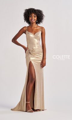 A woman stands against a plain background wearing the Colette CL8575 long prom dress featuring shimmering gold metallic stretch jersey, spaghetti straps, a ruched waist, and a thigh-high side slit.