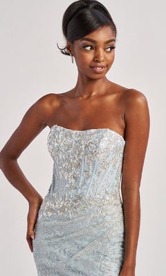 A woman poses with one hand on her hip, wearing the Colette CL8595 Long Prom Dress—a strapless light blue gown with silver embroidery—and looks to the side.