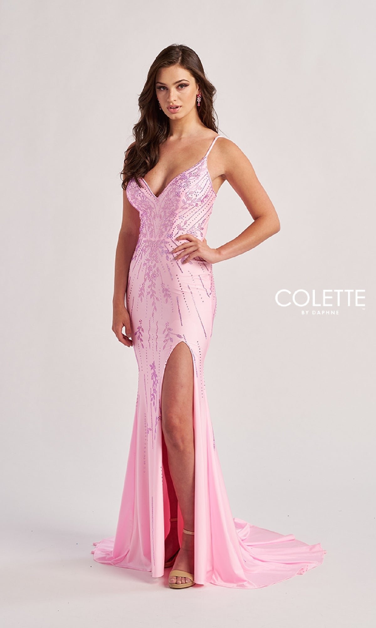 A woman poses in the Colette CL8620 long prom dress, featuring a fitted light pink beaded sequin design with thin straps, a thigh-high slit, and shimmering details. The text 