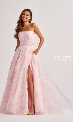 Woman wearing the Colette CL8635 long prom dress—a strapless, light pink floral a-line gown with pockets and a thigh-high slit—stands against a plain background.