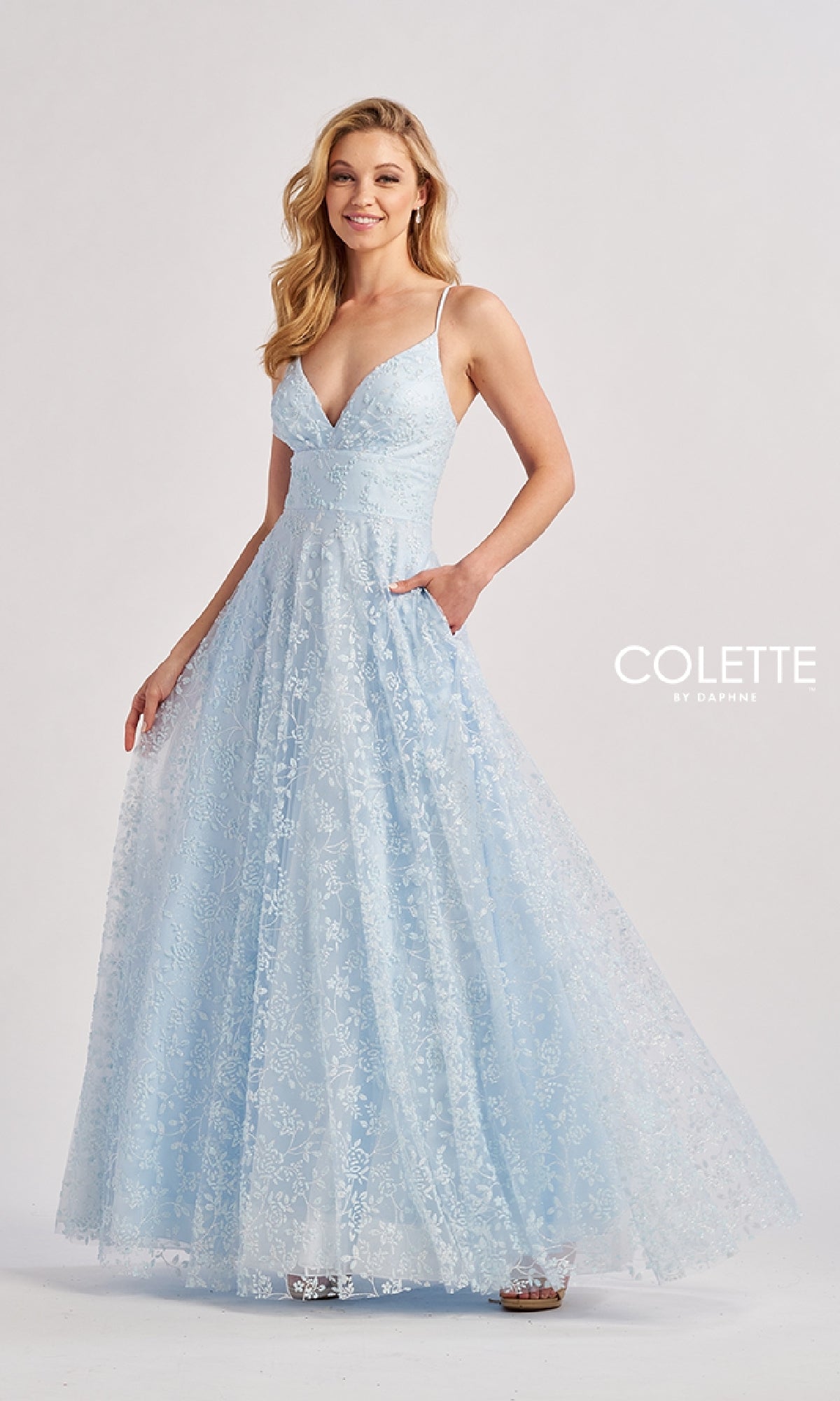 A woman models the Long Prom Dress: Colette CL8650—a light blue, floor-length sleeveless gown with thin straps, lace overlay, and an embroidered A-line skirt—standing against a plain background.