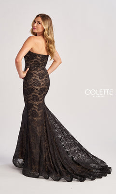A woman wearing the Colette CL8670 long prom dress, a strapless mermaid style with black lace and a long train, poses backward and looks over her shoulder against a plain white background.