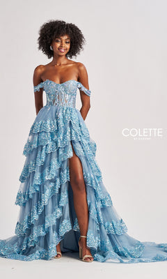 A woman stands against a plain background wearing the Long Prom Dress: Colette CL8690, an off-shoulder gown featuring a ruffle-tiered A-line skirt, lace details, and a thigh-high slit.