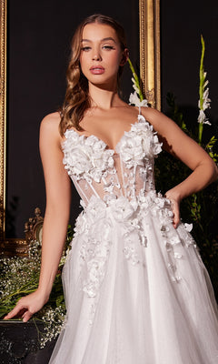 A woman in the Off-White Long Floral Prom Ball Gown CM321W stands before a dark backdrop with gold frames and greenery.