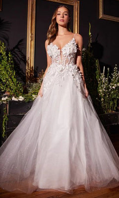A woman stands indoors among lush greenery and empty picture frames, wearing the Off-White Long Floral Prom Ball Gown CM321W with a floral-embellished skirt.