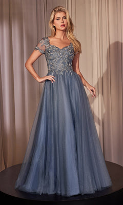 A woman stands in front of beige curtains wearing the Ladivine CM360 Short-Sleeve Blue Prom Ball Gown, featuring a beaded lace sweetheart bodice, sheer short sleeves, and a flowing tulle skirt.