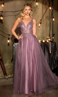 A woman stands in a dimly lit room with hanging lightbulbs, wearing the Ladivine CR880—a floor-length, sleeveless English Violet A-line prom dress with a deep V-neckline and beaded bodice.