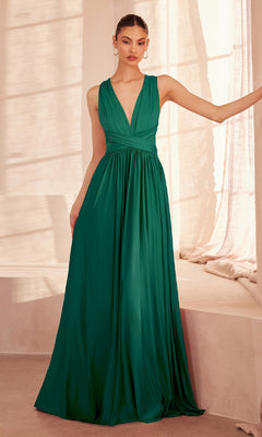 A woman stands indoors in the affordable Amoris CV01 Multi-Wrap Long A-Line Prom Dress—an emerald green, sleeveless floor-length formal gown with a deep V-neckline and gathered waist.