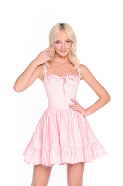 A woman poses against a white background wearing the Blush Pink Corset Summer Dress: Calista, featuring ruffled sleeves and a fitted bodice, with one hand on her hip and the other near her face.
