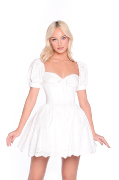 Woman wearing the Celine Fit-and-Flare Short White Grad Dress with puff sleeves and an eyelet skirt, posing against a plain white background—perfect for graduation.