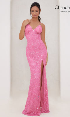 A woman wearing the Long Prom Dress 30118 by Chandalier—a fitted pink sequin gown with a v-neckline and thigh-high slit—stands against a light-colored background.