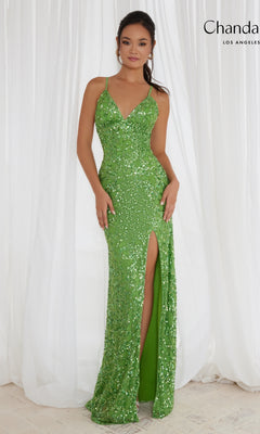 A woman in the Long Prom Dress 30118 by Chandalier—sleeveless, fitted, with sequins, v-neckline, and thigh-high slit—stands before white curtains.
