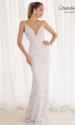 A woman poses in Chandalier’s Long Prom Dress 30157, a fitted, floor-length lavender gown featuring floral embroidery, an open back with thin straps, and a deep V-neckline, standing before sheer white curtains.