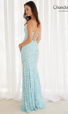 A woman stands with her back to the camera in a white, sheer-curtained room, wearing Chandalier's Long Prom Dress 30157—a light blue, floor-length gown with floral beading and a lace-up back.