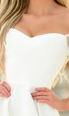 A woman wears the Chloe Short White Puff-Sleeve Party Dress, hands on her waist. Only her upper body is visible.