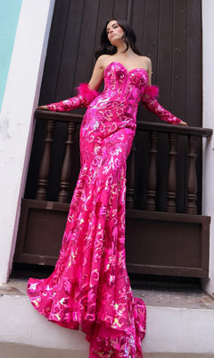A woman in the Strapless Sequin-Print Prom Dress with Gloves D1269 stands on a balcony against a dark wooden door, wearing matching feather-trimmed gloves.