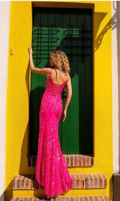 A woman wearing the Nox Anabel D1465 Fringed Long Sequin Prom Dress stands on steps facing a closed green door framed by a yellow wall.