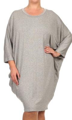 A person wearing a loose-fitting Short Casual Plus Size Dress with Dolman Sleeves in light gray stands with one hand on their hip against a plain background.