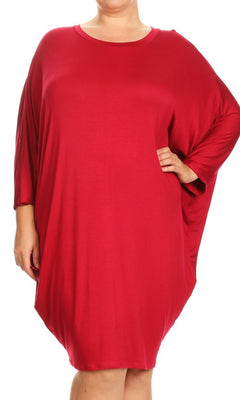 A person stands with one hand on their hip against a white background, wearing a loose-fitting red Short Casual Plus Size Dress with dolman sleeves.