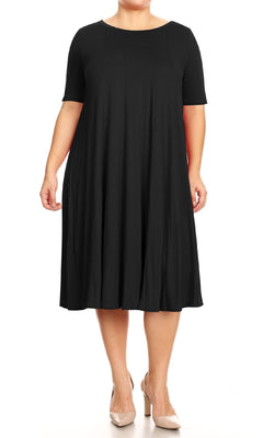 A person models the Plus-Size Jersey Knit Oversized A-Line Casual Dress in black, featuring a loose knee-length fit and short sleeves, paired with nude heels against a white background.
