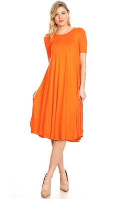 A woman wears the Short Sleeve Casual Oversized Jersey Knit Dress in orange, a loose-fitting, knee-length style with short sleeves and nude heels, standing against a plain white background.
