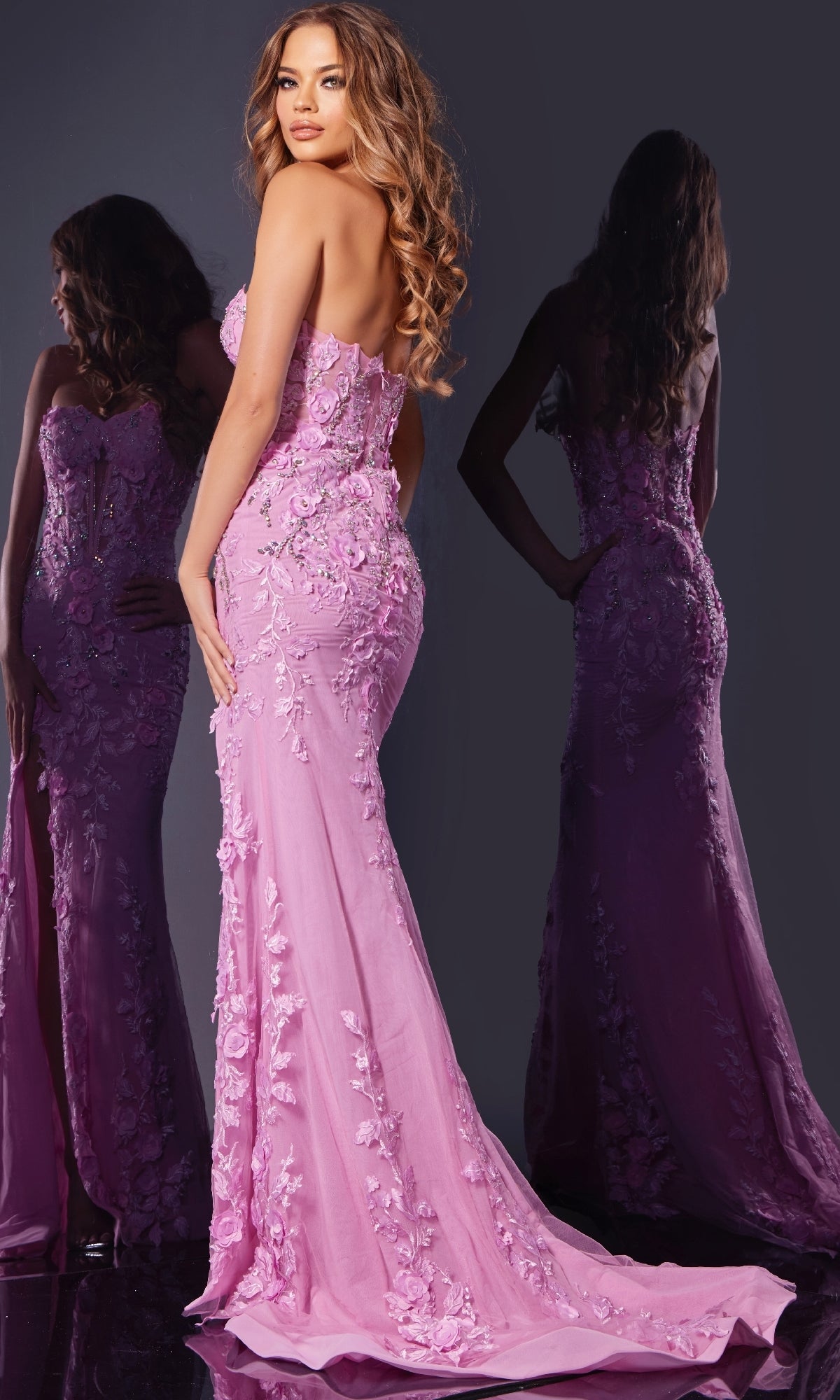 A woman wearing the Jovani D5107 long prom dress, strapless and floor-length in pink with 3D floral details, poses with her back to the camera beside her reflection in a mirror.