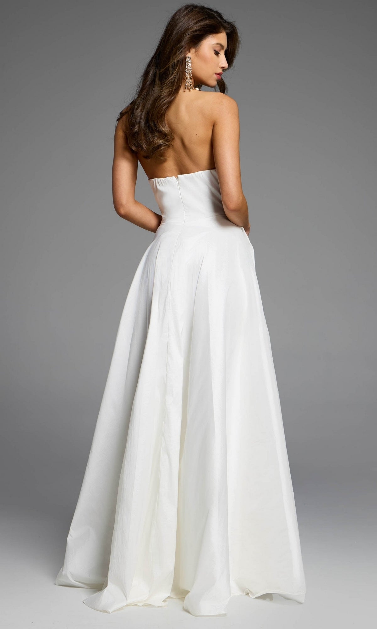 Back view of a woman wearing a white strapless A-line Jovani D5822 prom dress with a floor-length, full skirt.