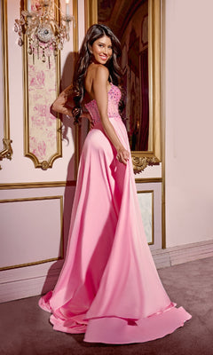 A woman wears the Pink Long Prom Dress: Jovani D6021, featuring a strapless beaded corset bodice, as she stands in an ornate room with gold trim, looking over her shoulder and holding her dress.
