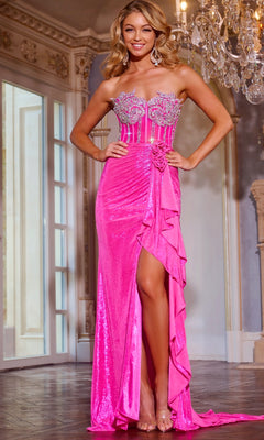 A woman poses indoors, smiling in the Jovani D6031 long prom dress—bright pink, strapless with a beaded corset bodice, high slit, ruffle detail—and clear high heels, her hand resting on her hip.