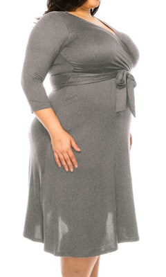 A person wears the Faux-Wrap Plus-Size Casual Dress with Sleeves in gray, featuring long sleeves, a knee-length hem, and a waist tie, standing against a white background.