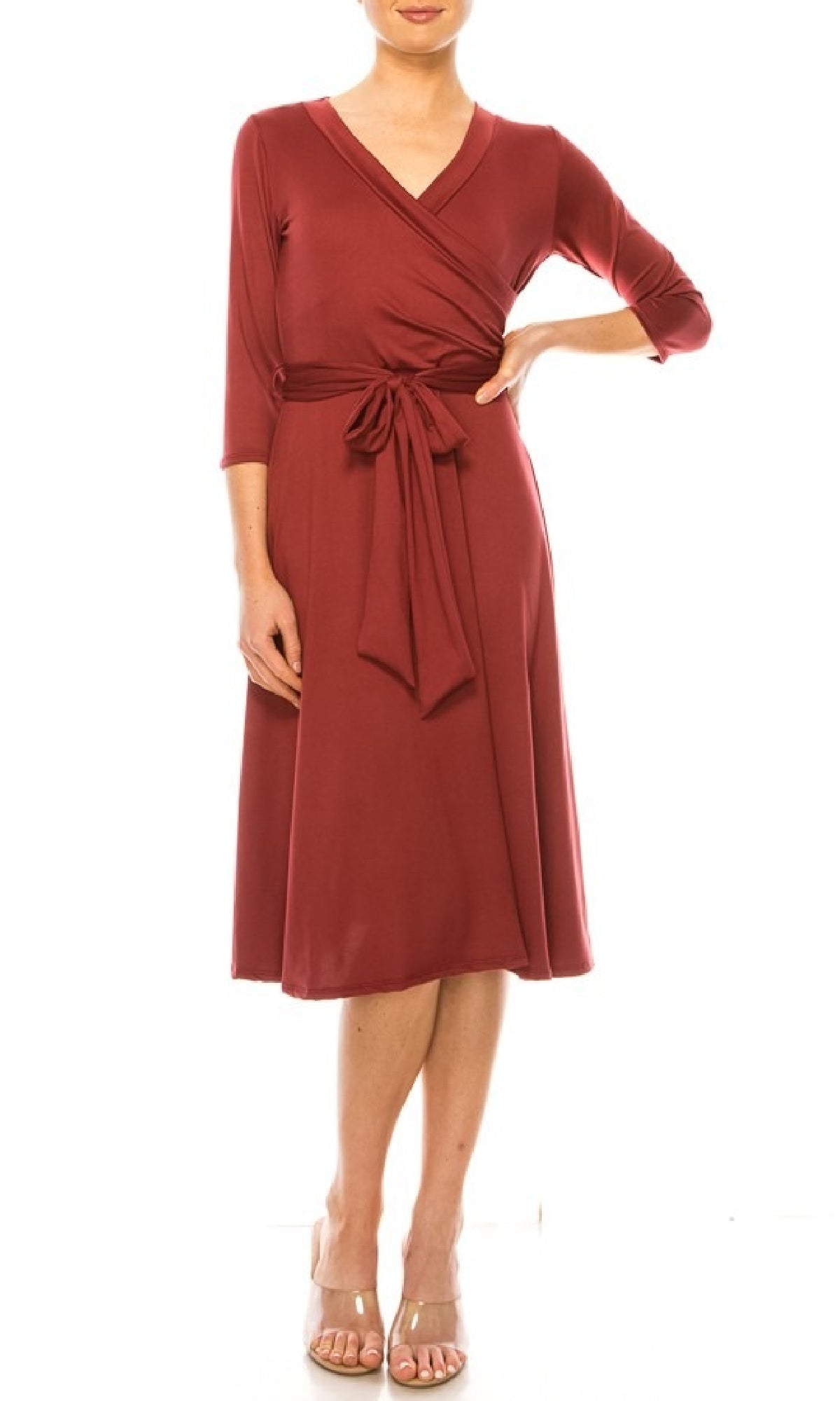 A woman in the Faux-Wrap Casual Short Dress with Sleeves—knee-length, long-sleeved, burgundy with a v-neck and waist tie—stands in open-toe heels against a white background.