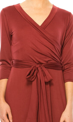 Person wearing the Faux-Wrap Casual Short Dress with Sleeves, featuring long sleeves, a V-neckline, tied waist sash, faux-wrap design, and knee-length hem in burgundy.