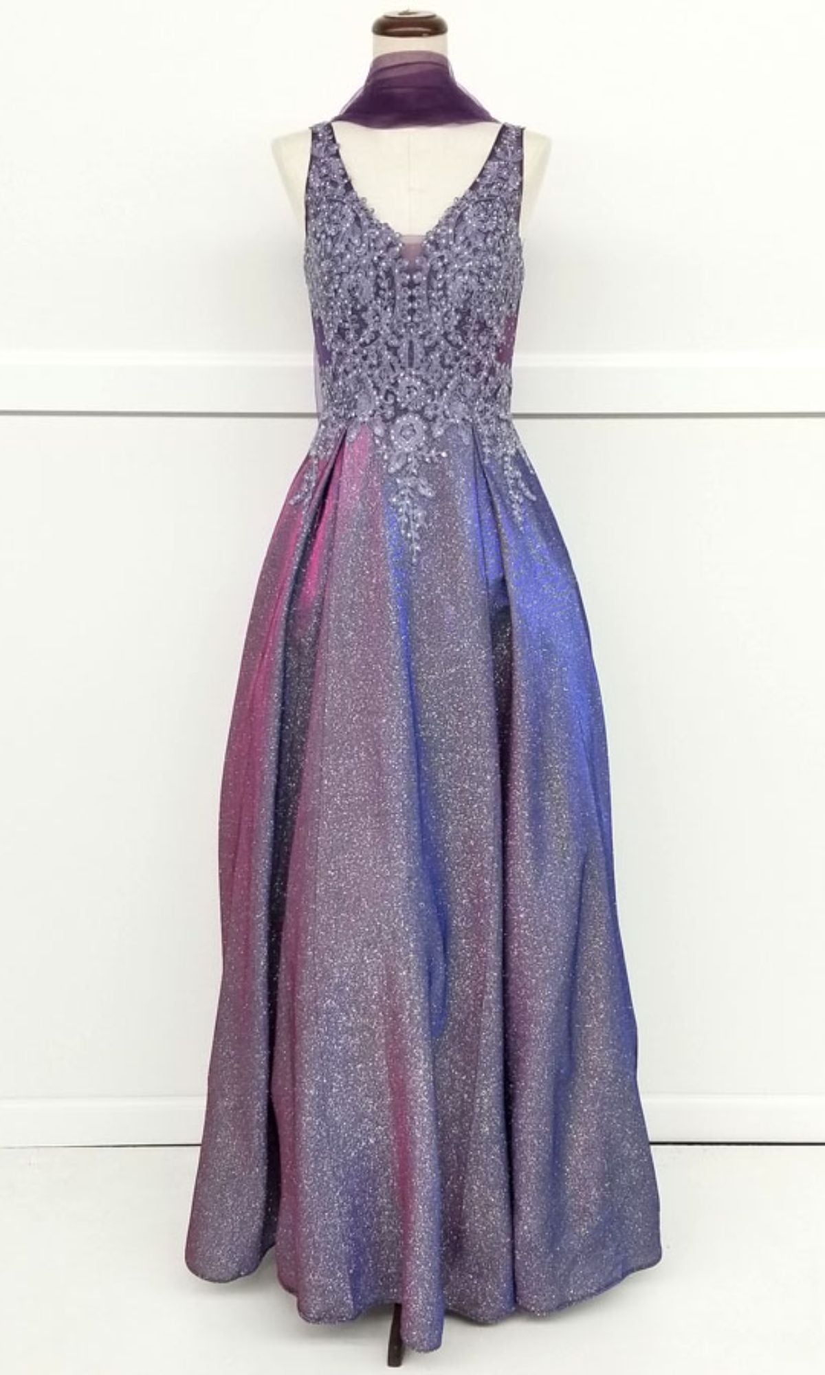 The Chicas DM4017 Lace-Bodice Long Glitter Prom Dress features a sleeveless, floor-length embroidered lace bodice and a sparkling ombre skirt in purple, pink, and blue, shown on a dress form.