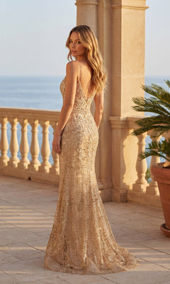 A woman stands on a stone terrace by the sea, next to a potted plant, wearing the Chicas DM4029 gold, sleeveless, floor-length prom dress with sequin embellishments.