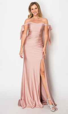 A woman wearing the Long Prom Dress: Chicas DM8010 in mocha, featuring an off-the-shoulder neckline and a thigh-high slit, stands smiling against a plain background, paired with silver heels.