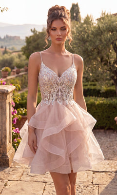 Against a lush garden backdrop with vibrant greenery and a stone pathway, a woman models the Chicas DM8031 Short Homecoming Dress in Rose—a pale pink, fit-and-flare style featuring thin straps and intricate lace detailing on the bodice.