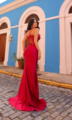 A woman wearing the Lace-Up Corset-Bodice Long Satin Prom Dress E1292 stands on a cobblestone street in front of a blue and white building, glancing over her shoulder.