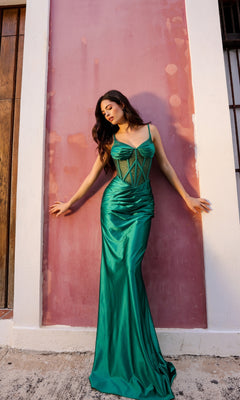 A woman wearing the Lace-Up Corset-Bodice Long Satin Prom Dress E1292 in emerald green stands against a pink and white wall, looking to the side with her hands touching the wall.