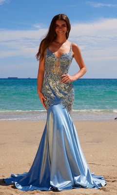 Wearing the Nox Anabel E1532, a long light blue mermaid prom dress with beaded embroidery, a woman stands on a sandy beach with the ocean and sky as a breathtaking backdrop.