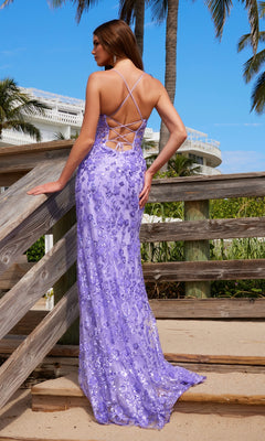 A woman in the Nox Anabel E1710 Long Purple Sequin Prom Dress with a lace-up back stands on a wooden walkway by the beach, facing away. The shimmering gown catches the light, creating an elegant and unforgettable scene.