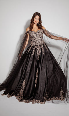 A woman wears the Quinceanera Dress EK1002 by Eureka—a black, off-the-shoulder gown with gold embroidery, sheer tulle sleeves, and a lace-up back—standing against a plain background.