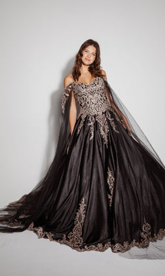 A woman wearing the Quinceanera Dress EK1002 By Eureka, an off-the-shoulder black ball gown with gold embroidery, poses against a plain white background, highlighting its classic elegance.