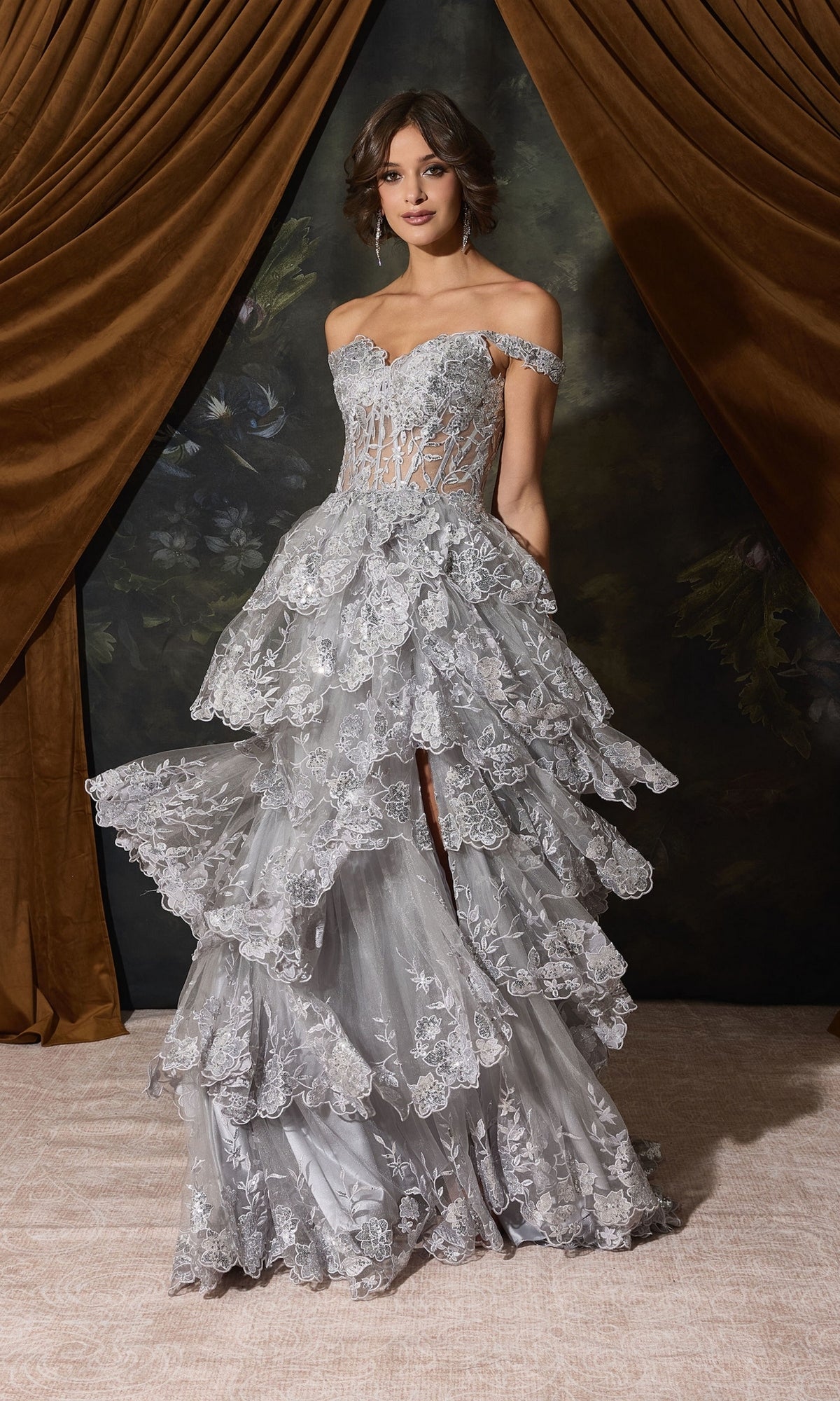 A person wears the Off-Shoulder Long Ruffle Prom Dress: Eureka EK102, a silver off-the-shoulder dress with an intricate lace bodice and a high-low tiered ruffle skirt.