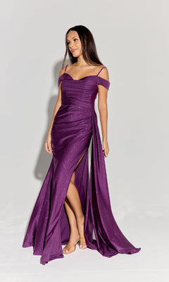 A woman poses against a plain background wearing the Eureka EK107 Long Ruched Jersey Prom Dress, a floor-length purple off-the-shoulder gown with a side slit and sparkling fabric.