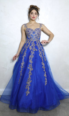 A woman stands against a light textured wall, wearing the Eureka EK115 Long Blue Sweetheart Prom Gown featuring embroidered florals, gold lace embellishments, and sheer straps.